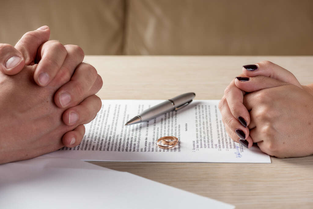 Couple sitting across the table from each other over divorce papers